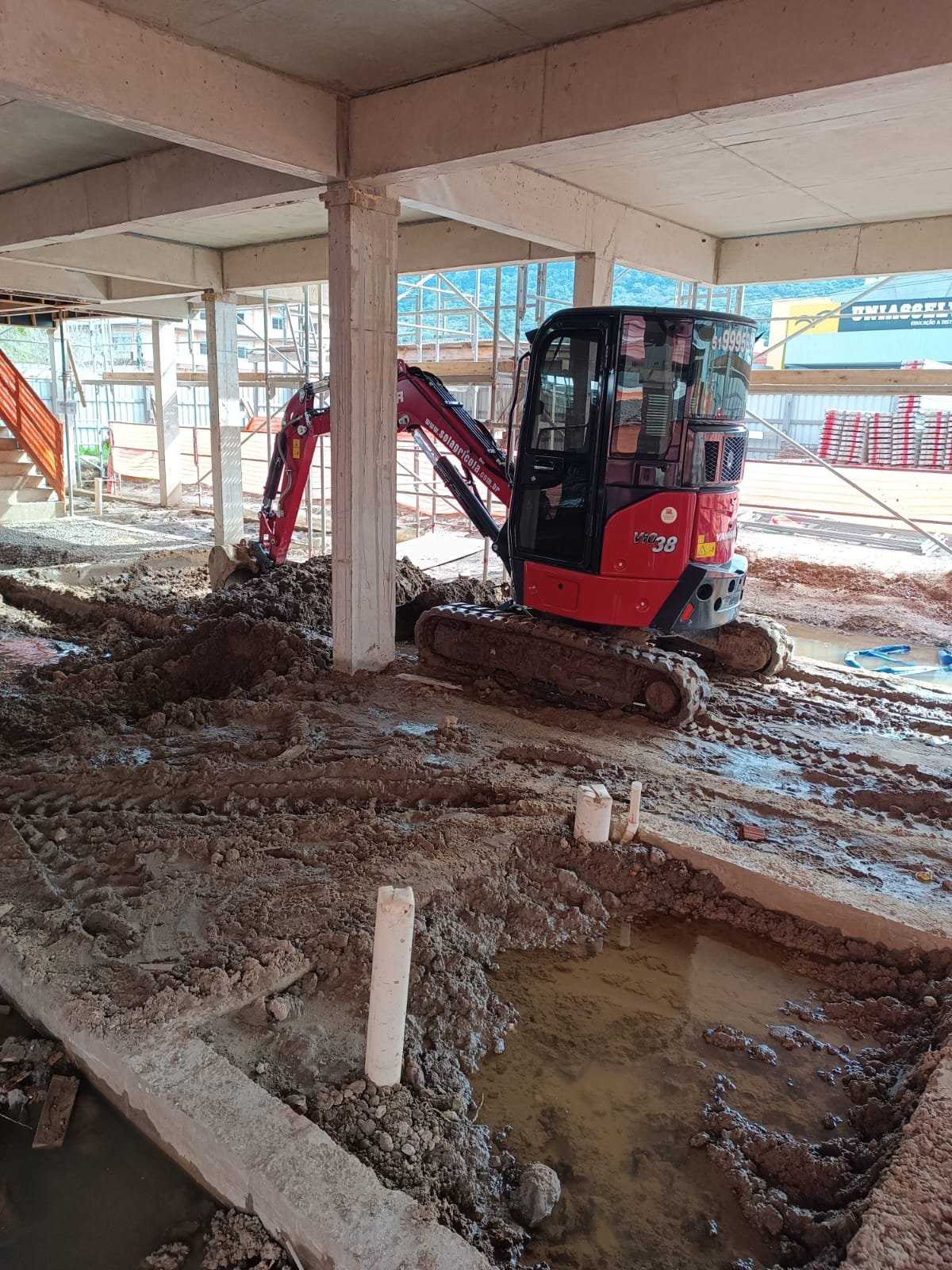 Terreno nivelado com marcação de faixa de concreto ao lado de estrutura industrial